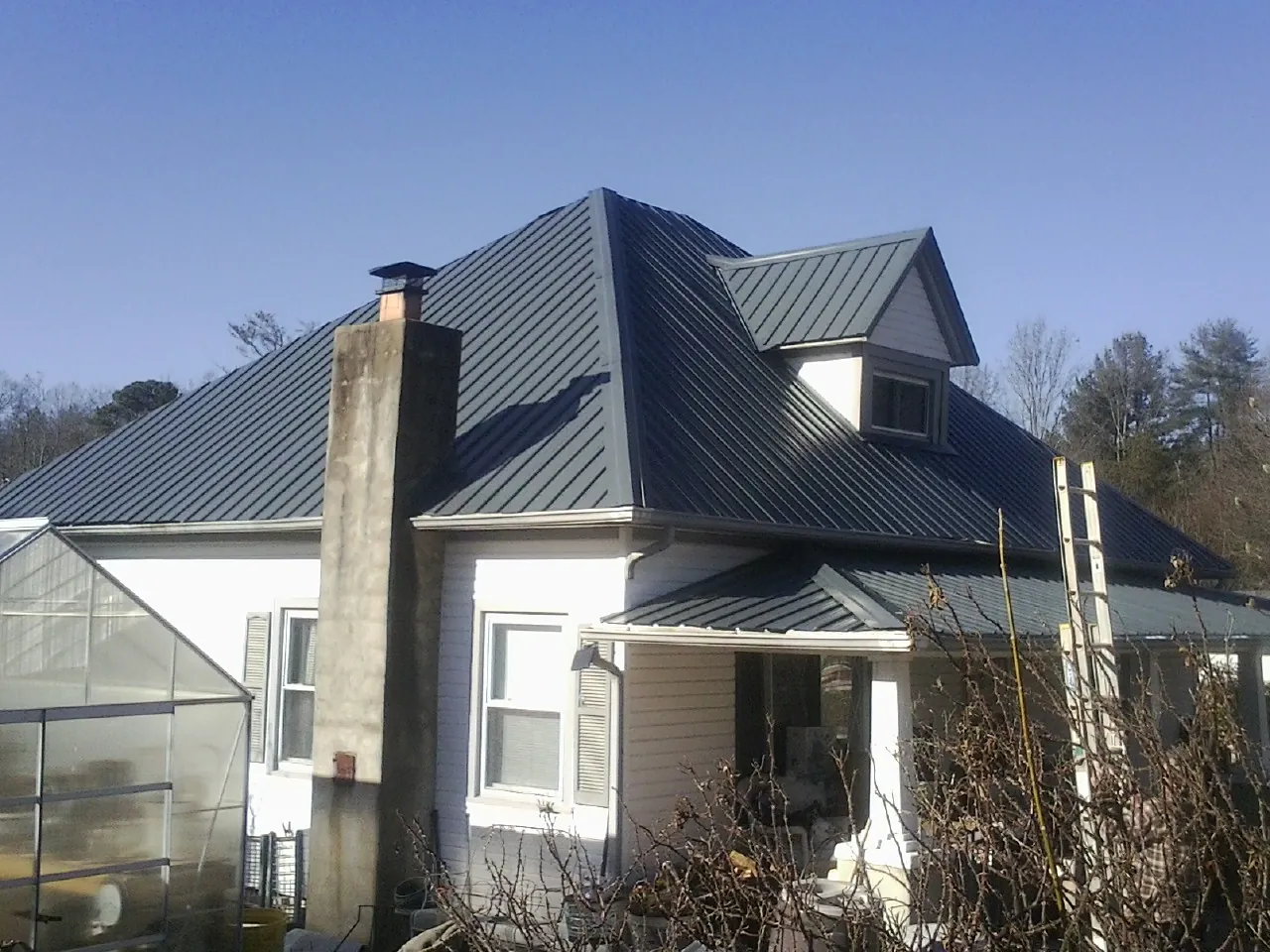 Dark blue standing seam metal roof on a white farmhouse with dormer — Slate & Tile Roof Repair by Roofing Brothers in Mayview