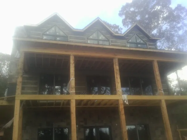 Dormers and porch framing on a large log home under construction — Roof Coating work by our crew in Mayview