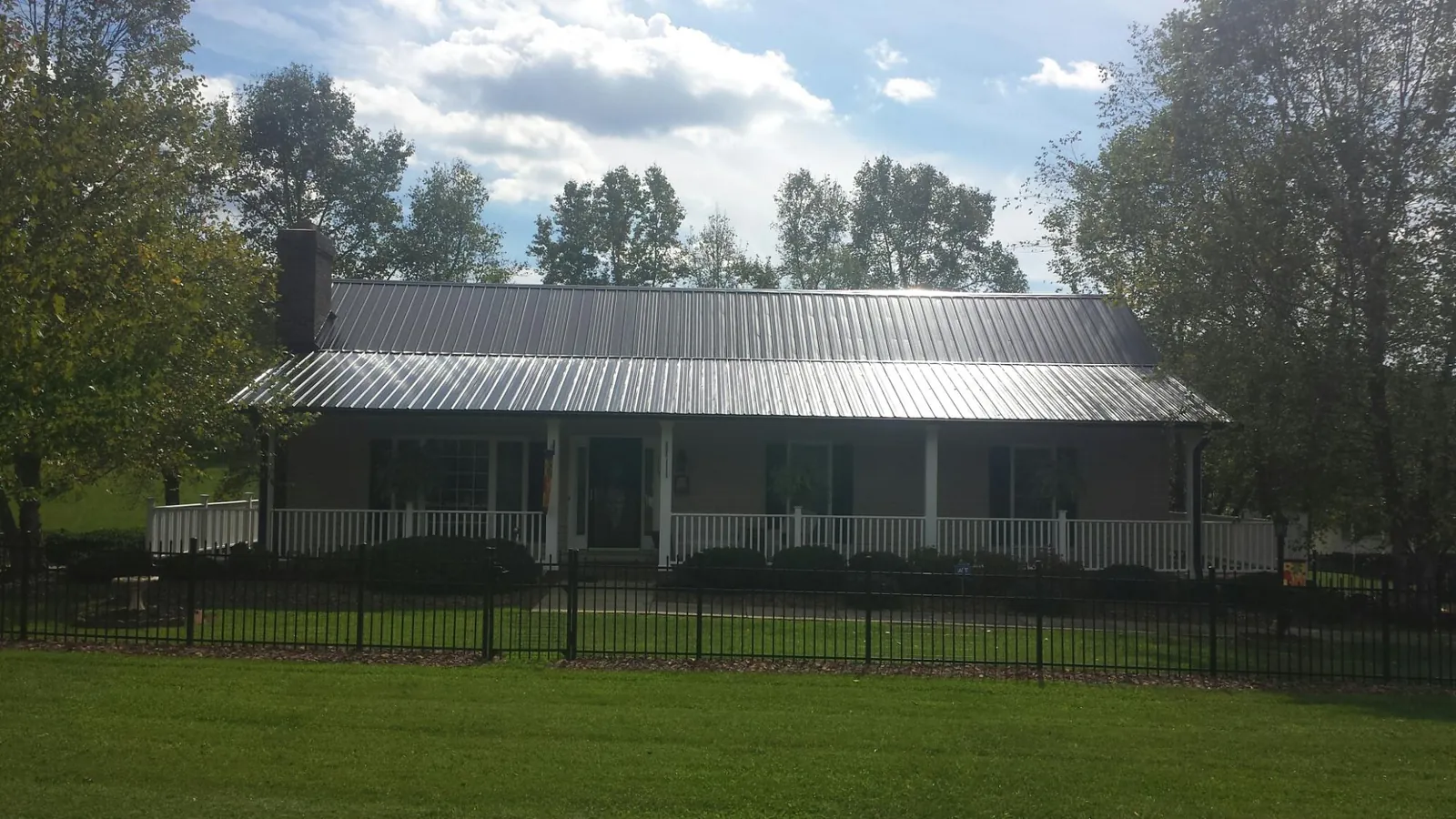 Gray metal roof on a brick ranch with a full width front porch — Gutter Guard Installation work by our crew in Mayview